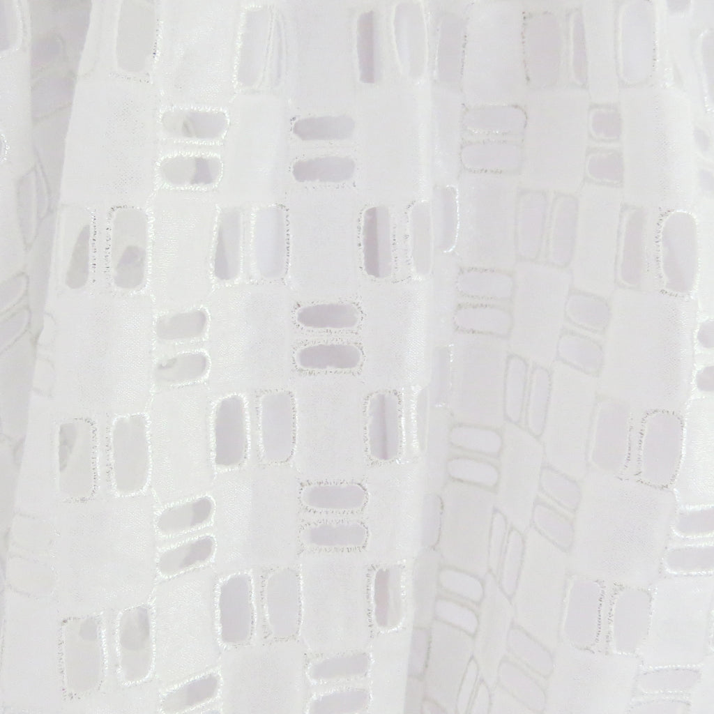 Summer silver foil cotton geometric broderie anglaise fabric close up.