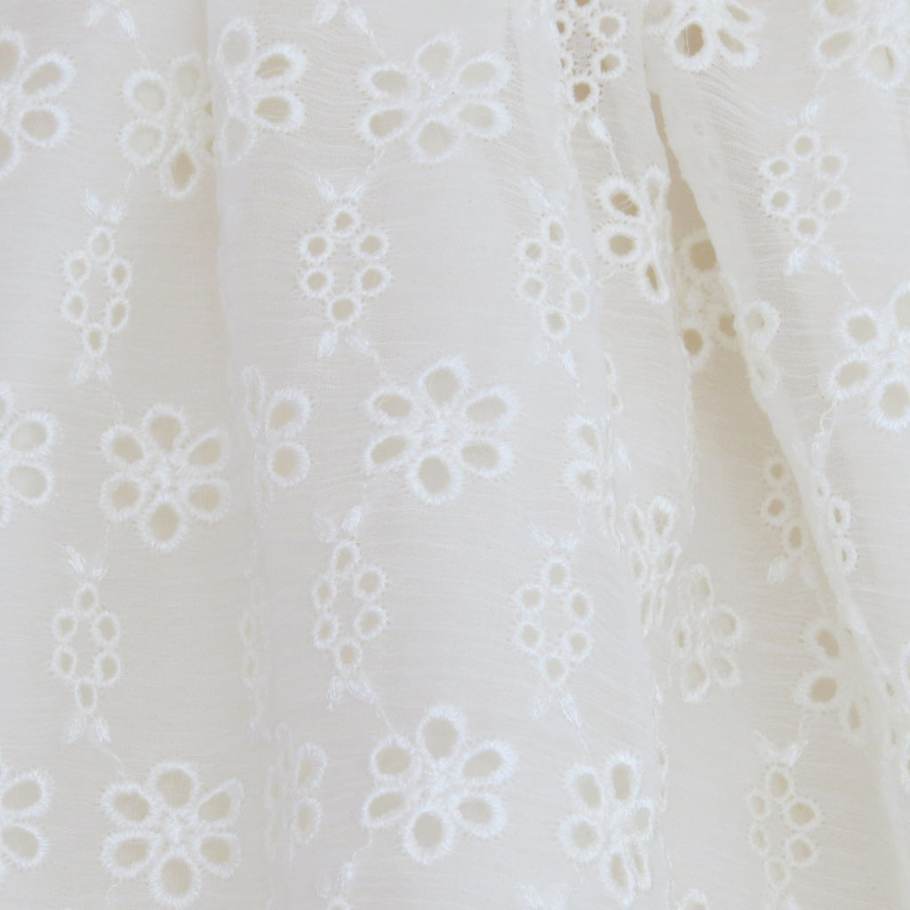 Summer Childs cream silk broderie anglaise dress fabric close up.