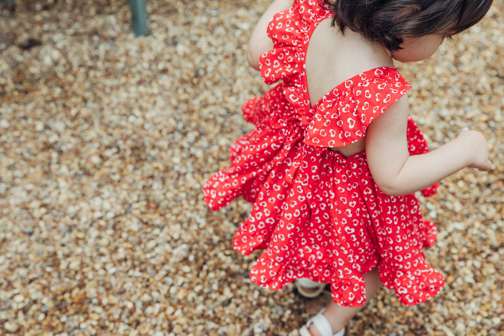 Childs Summer red conversational heart print dress in bright red and white with frill sleeves.
